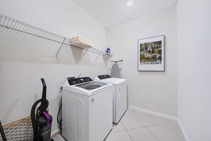 A laundry room with two washing machines, a drying rack, and a vacuum cleaner. - 10BR house with private pool and game room (Clermont)