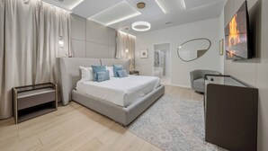 A modern bedroom with a large bed, bedside tables, a TV, and a mirror. - 10BR house at Windsor Cay Resort (Clermont)