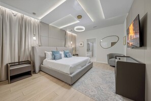Ein modernes Schlafzimmer mit einem großen Bett, Nachttischen, einem Fernseher und einem Spiegel.