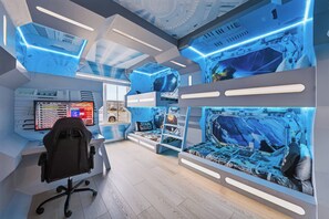 Una habitación con espacio para juegos, que incluye un monitor, una silla y decoración temática de Star Wars.