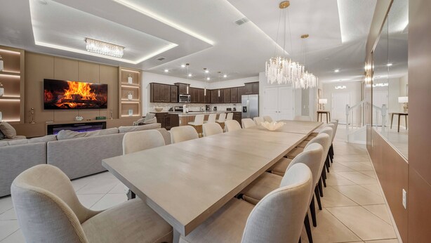 A modern kitchen with dark wood cabinets, a large island, and a flat-screen TV. - 10BR house at Windsor Cay Resort (Clermont)