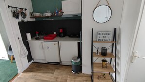 A compact kitchen with a sink, a coffee maker, and a small refrigerator. There is a welcome sign on a shelf, and a bicycle is visible in the corner. - Cosy T2 with view in Morlaix between station and town center (Morlaix)