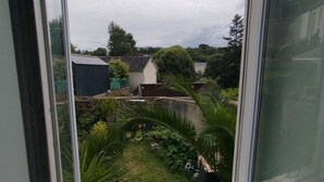 A view from a window overlooking a garden with a variety of plants and a small shed. - Cosy T2 with view in Morlaix between station and town center (Morlaix)