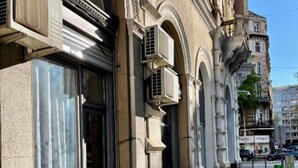 Een gebouw met grote ramen, airconditioners en een trottoir.