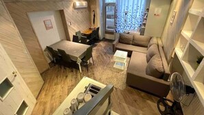 Een moderne woonkamer met een eethoek, een bank en een ventilator.