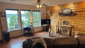 A cozy living room with a fireplace, a mounted deer head, and a television.