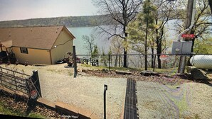 A house by a lake with a fenced yard, a gravel path, and a metal fence.