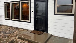 A house with white siding, a black front door, and three windows with black frames.