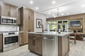 A modern kitchen with wooden cabinets, stainless steel appliances, and a large island. - Elegant Deer Valley 2BR-Private Hot Tub-Walk to Deer Valley Resort (Park City)