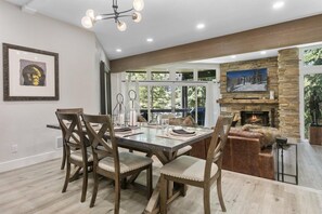 A dining area with a table and chairs, a fireplace, and a view of the outdoors. - Elegant Deer Valley 2BR-Private Hot Tub-Walk to Deer Valley Resort (Park City)