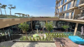 Een moderne buitenplaats met zitgedeeltes, een zwembad en uitzicht op een hoog gebouw.