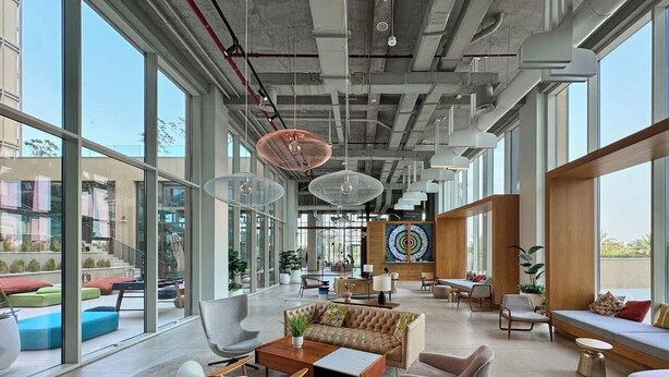 Een ruime lobby met moderne meubels, grote ramen en een centraal kunstwerk.