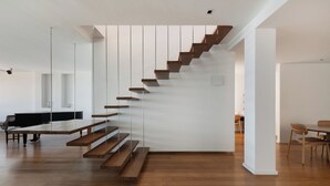 Un interno moderno con una scala in legno, un'area pranzo e un pianoforte.