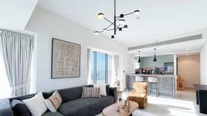 A modern living room with a sofa, coffee table, and a view of the city. - Modern 2BR Haven in Golf Gate Pool & Gym Access (Dubai)