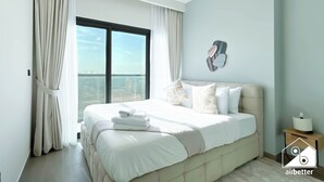 A modern bedroom with a large bed, a view of the city, and a minimalist decor. - Modern 2BR Haven in Golf Gate Pool & Gym Access (Dubai)