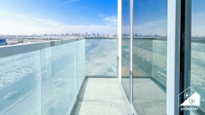 A high-rise building with a glass balcony overlooking a cityscape. - Modern 2BR Haven in Golf Gate Pool & Gym Access (Dubai)