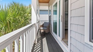 A covered porch with a ceiling fan, a wicker chair, and a small table. - Coastal Comfort ~ your own Heated Pool ~ Golf Cart (North Myrtle Beach)