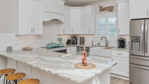 A modern kitchen with white cabinetry, a marble island, and stainless steel appliances. - Coastal Comfort ~ your own Heated Pool ~ Golf Cart (North Myrtle Beach)