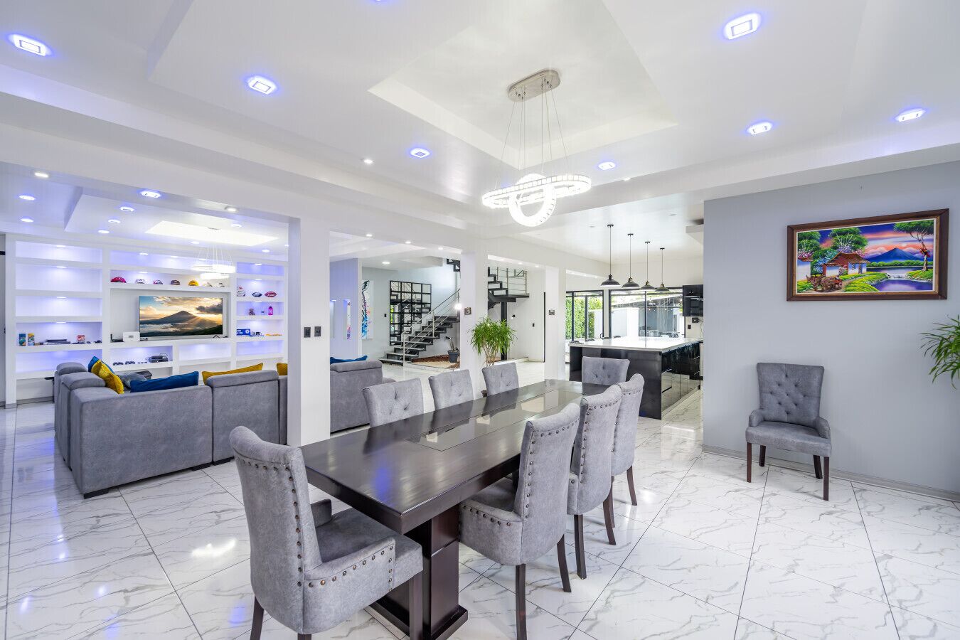 Una sala de estar moderna con comedor, cocina y una escalera que sube a un nivel superior.