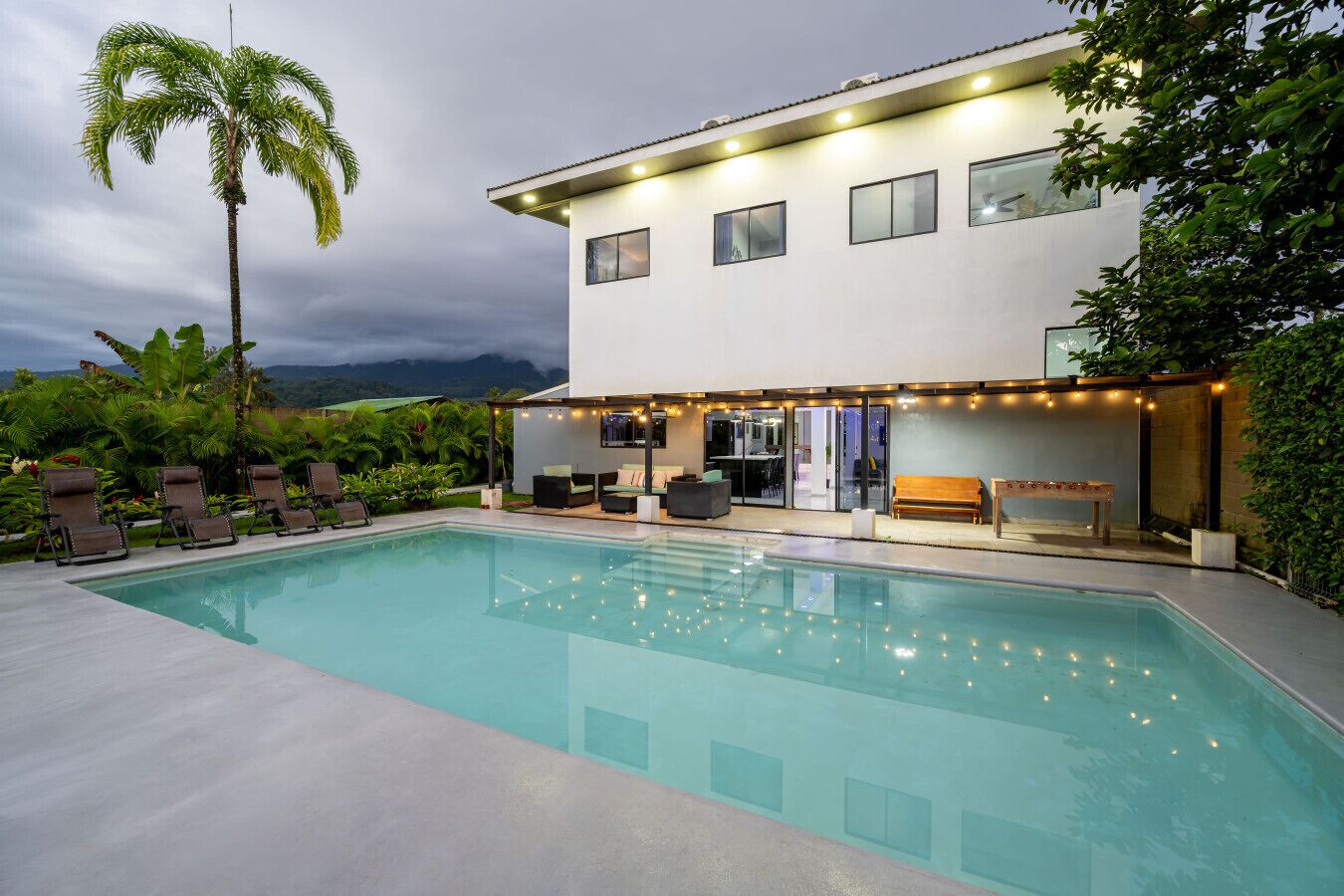 Ein modernes, zweistöckiges Haus mit Swimmingpool, Außenbereich und Bergblick.