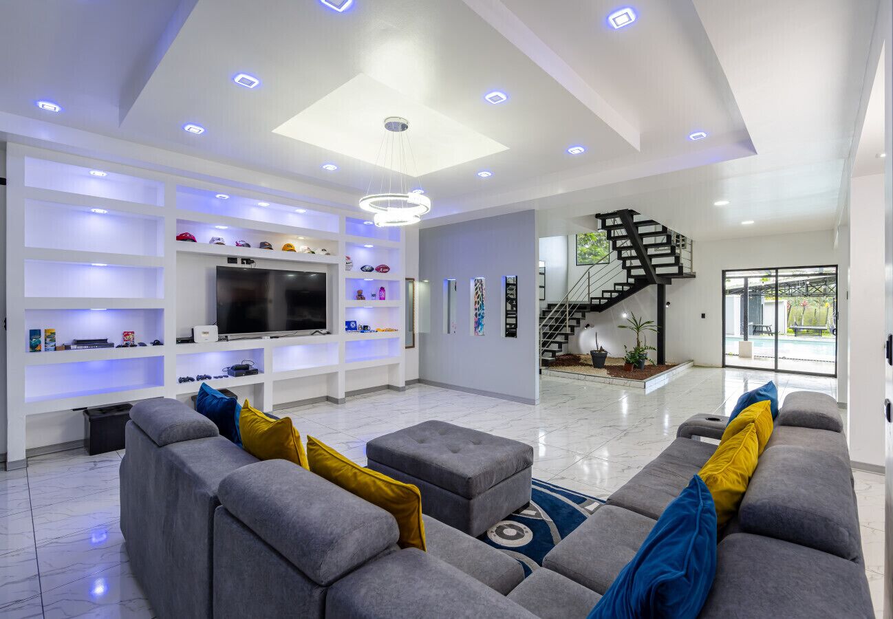 Una sala de estar moderna con un sofá gris, un televisor de pantalla plana y estantes con diversos objetos.