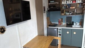 Una cucina compatta con un tavolo in legno, una lavastoviglie integrata e un mobile grigio.