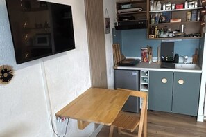 Eine kompakte Küche mit Holztisch, eingebautem Geschirrspüler und einem grauen Schrank.