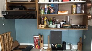 Una cucina con un piano di lavoro, un lavello e scaffali soprastanti con diversi oggetti da cucina.