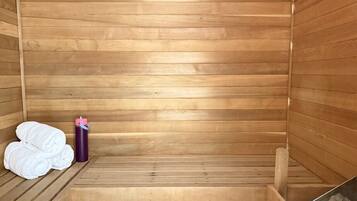 A sauna with wooden benches, a towel stack, and a water bottle.