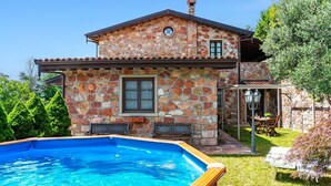 Una casa de piedra con piscina, un patio y un jardín.