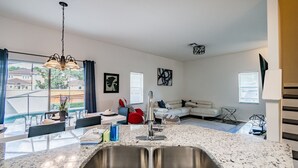 Eine moderne Küche mit einer Spüle, einem Essbereich mit Stühlen, einem roten Stuhl und einem weißen Sofa.
