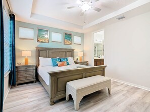 A bedroom with a bed, bedside tables, a bench, a ceiling fan, and artwork on the walls. - 5BR Solara • Prvt Pool • Arcade • Near Disney (Kissimmee)