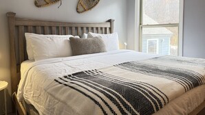 Una camera da letto con una testiera in legno, biancheria da letto bianca e due elementi decorativi a parete.