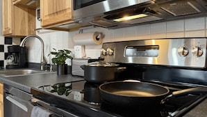 Una cucina moderna con elettrodomestici in acciaio inossidabile, mobili in legno e un piano di lavoro nero.