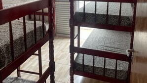 A room with two bunk beds, a ceiling fan, and a window with blinds. - Beachfront apartment (Ubatuba)