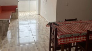 A dining area with a checkered tablecloth, a ceiling fan, and a view through a glass door to an outdoor balcony. - Beachfront apartment (Ubatuba)