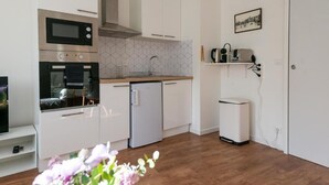 Eine kleine Küche mit weißen Schränken, einer Mikrowelle, einem Backofen, einem Spülbecken und einem kleinen Kühlschrank.