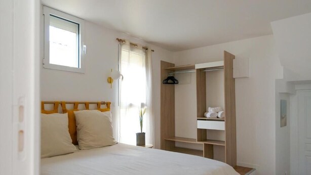 Ein Schlafzimmer mit Bett, Kleiderschrank und Fenster.