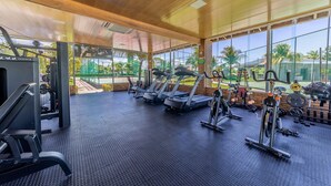 Un gimnasio con cintas de correr, máquinas de pesas y un amplio ventanal con vistas al exterior.