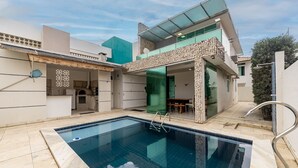 Una casa moderna con piscina, comedor y fachada de piedra.