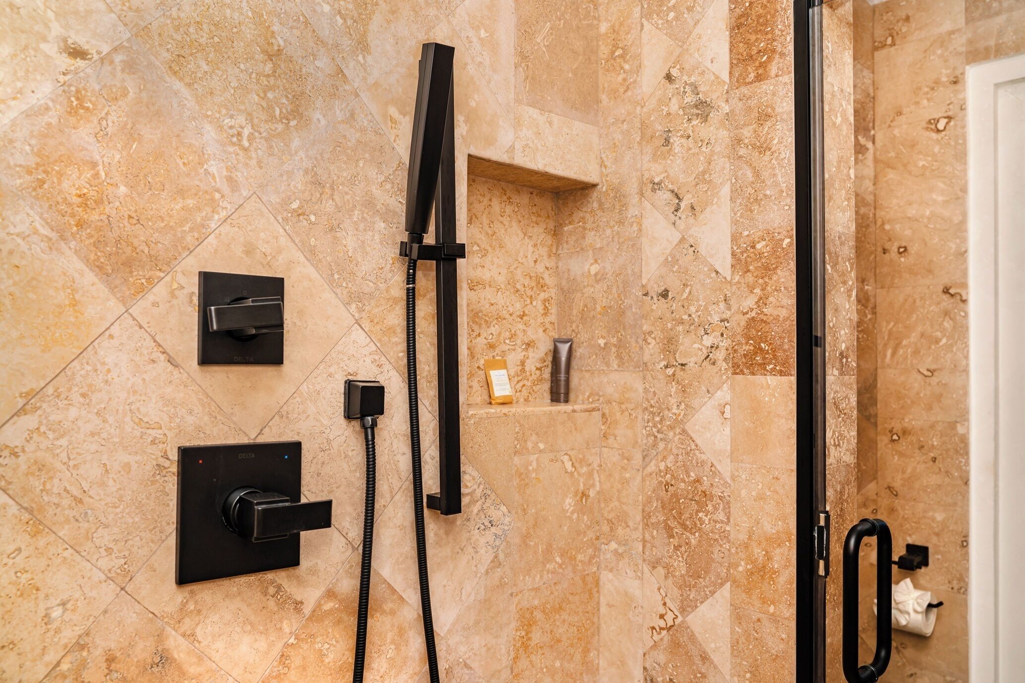 A modern bathroom with a glass-enclosed shower, a handheld showerhead, and a wall-mounted control panel.