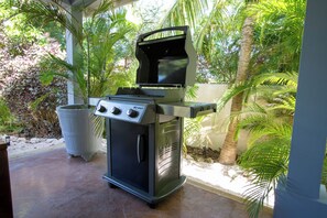 Een buitengrillgedeelte met een ingebouwde gasplaat, een grote pan en een plant in een pot ernaast.