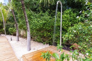 A wooden deck leading to a garden area with a water feature and lush greenery. - Little Bali Curaçao: Exotic Caribbean Oasis (Grote Berg)