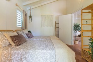 A bedroom with a large bed, a wooden ladder, and a hanging macrame wall hanging. - Little Bali Curaçao: Exotic Caribbean Oasis (Grote Berg)
