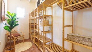 A room with wooden shelves holding baskets and a wicker chair. - Little Bali Curaçao: Exotic Caribbean Oasis (Grote Berg)