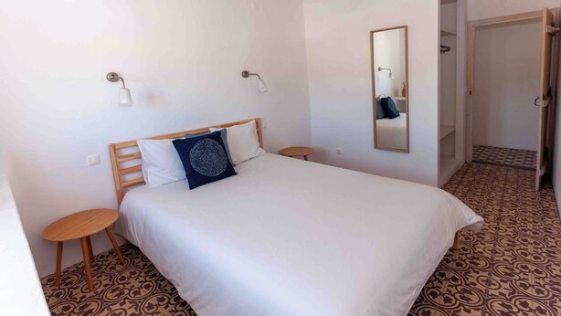 Ein Schlafzimmer mit einem Bett, zwei Nachttischen, einem Wandspiegel und einem Bodenbelag mit Muster.