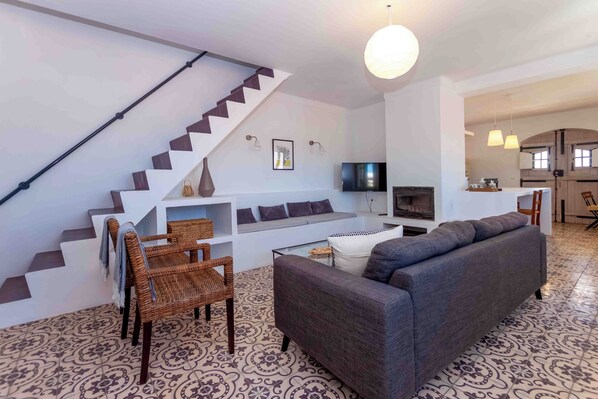 A modern living room with a staircase, a sofa, a coffee table, and a TV.