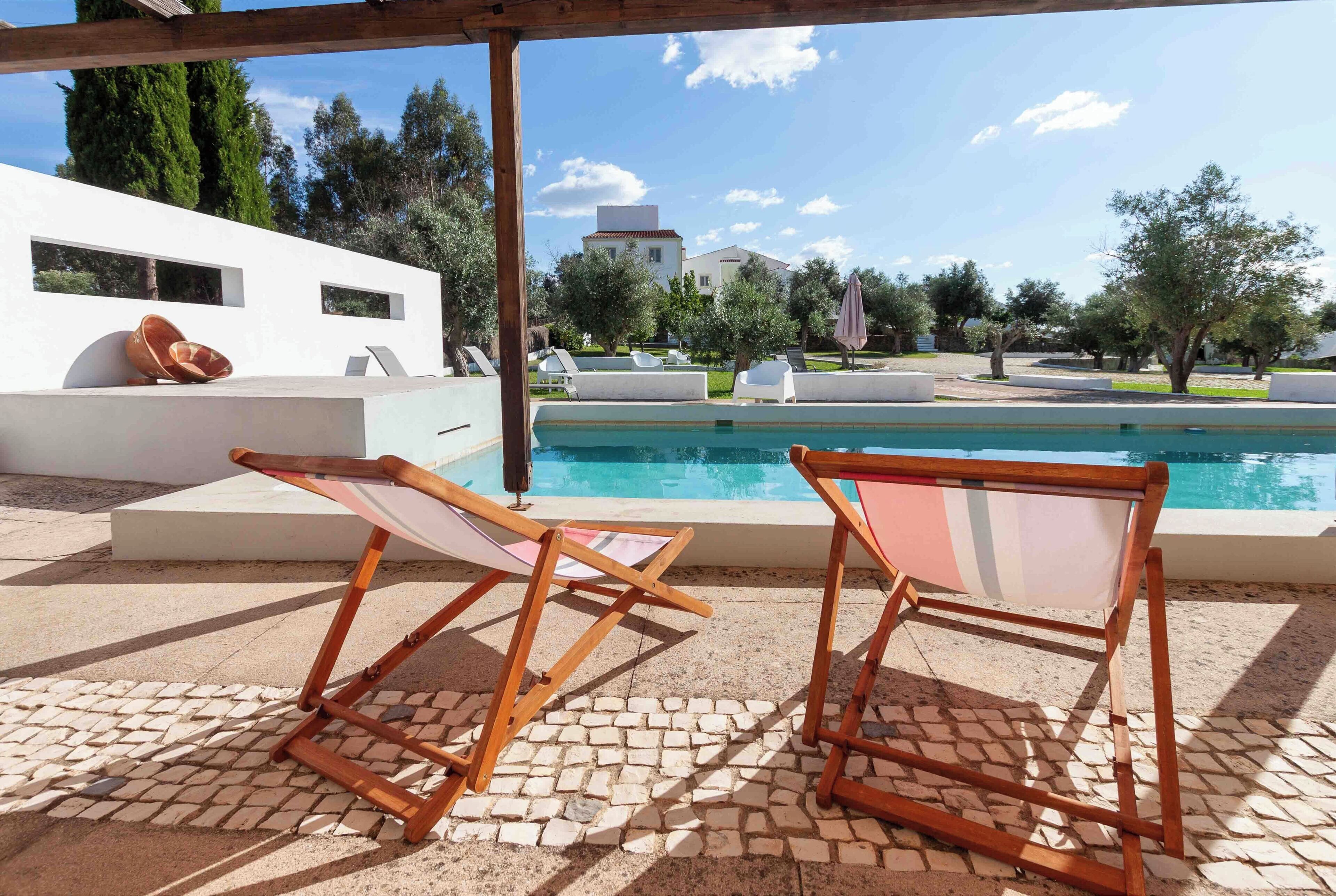 En säsongsöppen utomhuspool, parasoller och solstolar