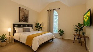 Une chambre à coucher avec un lit, des tables de chevet, une fenêtre avec des rideaux et un tableau au mur.