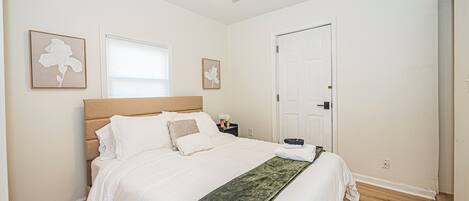 Une chambre à coucher avec un lit, un ventilateur de plafond, une table de chevet et une porte.